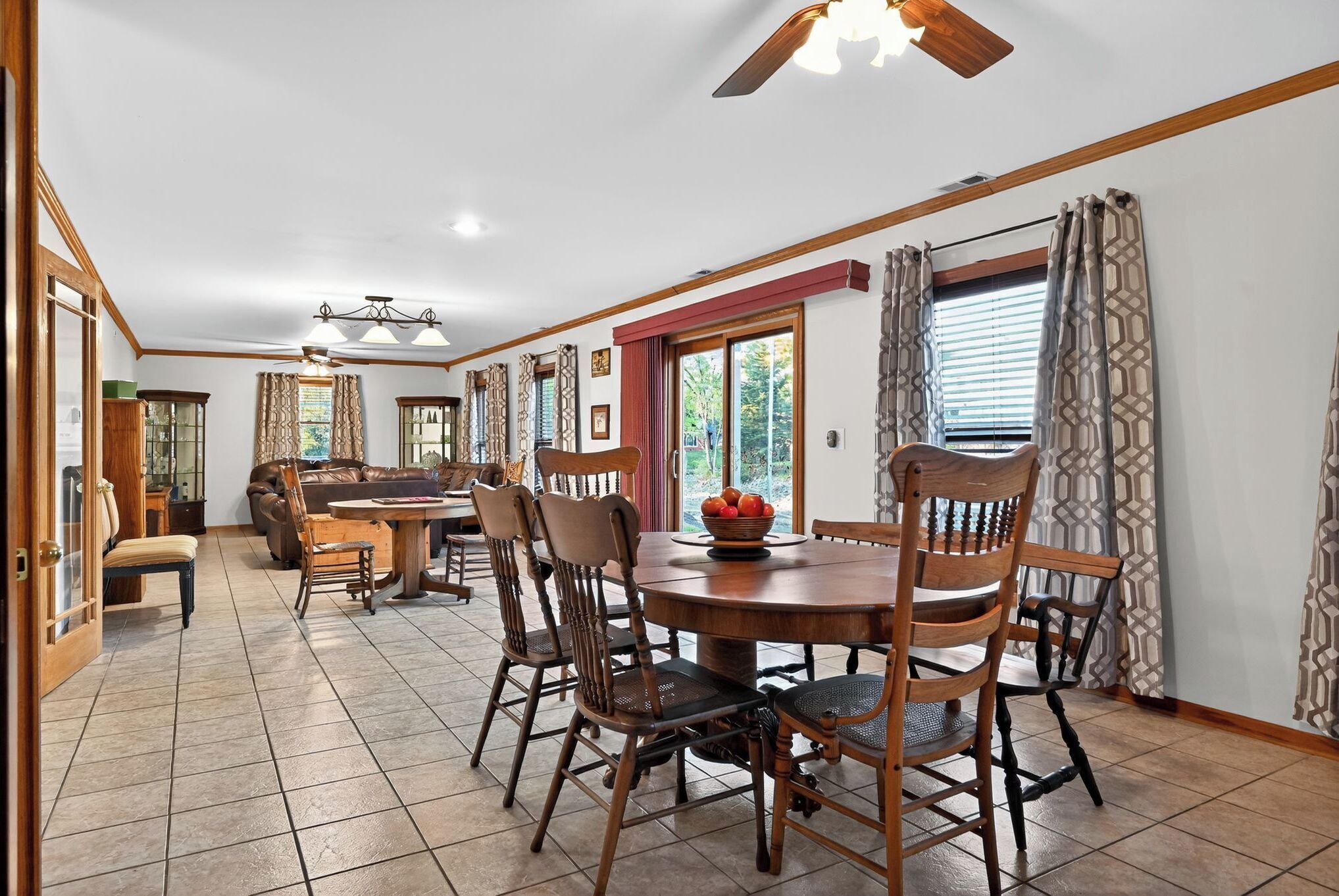 A dining area with a round wooden table, six chairs, and a ceiling fan.
