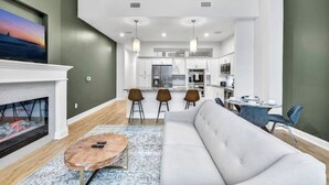 A modern living room with a fireplace, a sofa, and a dining area with chairs and a table. - Luxury Condo Heart of Downtown / 98/100 Walk Score (Cleveland)