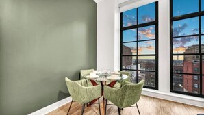 A dining area with a round table and four chairs, large windows with a city view, and wooden flooring. - Stunning Luxury Downtown Condo in Playhouse Square (Cleveland)