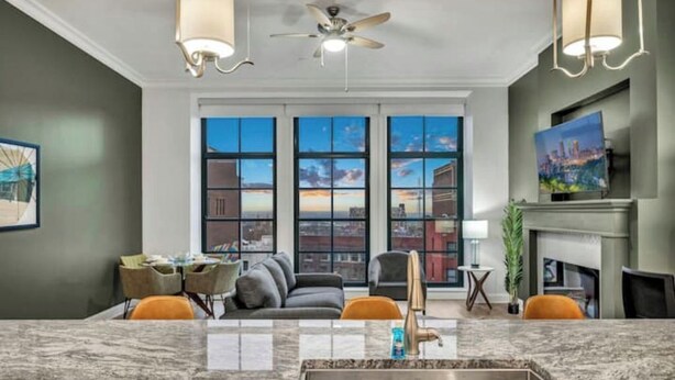 A modern living room with a large window, a fireplace, and a dining area. - Stunning Luxury Downtown Condo in Playhouse Square (Cleveland)