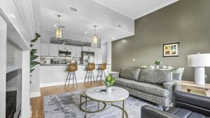 Un salon moderne avec un canapé gris, une table basse et un coin repas avec des chaises.