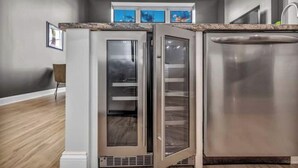 Une cuisine compacte dotée d’un réfrigérateur et d’un lave-vaisselle intégrés, d’une fenêtre au-dessus de l’évier et d’un plancher en bois.