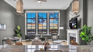 A modern kitchen with a large island, a dining area with a view, and a living room with a fireplace. - The Halle Downtown 1BD / FREE Parking/Gym/Security (Cleveland)