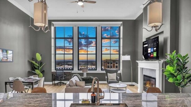 A modern kitchen with a large island, a dining area with a view, and a living room with a fireplace. - The Halle Downtown 1BD / FREE Parking/Gym/Security (Cleveland)