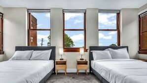 Habitación de hotel con dos camas, un ventanal con vistas y piso alfombrado.