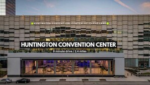 El Centro de Convenciones Huntington, con un diseño arquitectónico moderno, presenta una llamativa fachada de vidrio y un letrero que indica una distancia de 9 minutos en coche desde Cleveland.