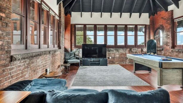 Una habitación acogedora con mesa de billar, asientos cómodos y amplios ventanales con vistas.