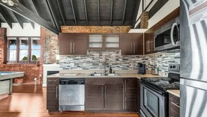 Una cocina moderna con armarios oscuros, salpicadero de azulejos, electrodomésticos de acero inoxidable y suelo de madera.
