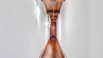 A long, narrow hallway with wooden flooring and a wooden ceiling structure.