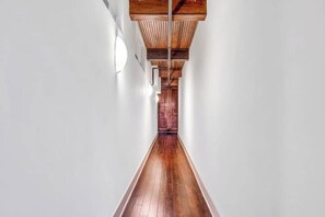 A long, narrow hallway with wooden flooring and a wooden ceiling structure. - Urban Industrial Penthouse | Game Room Pool Table (Cleveland)
