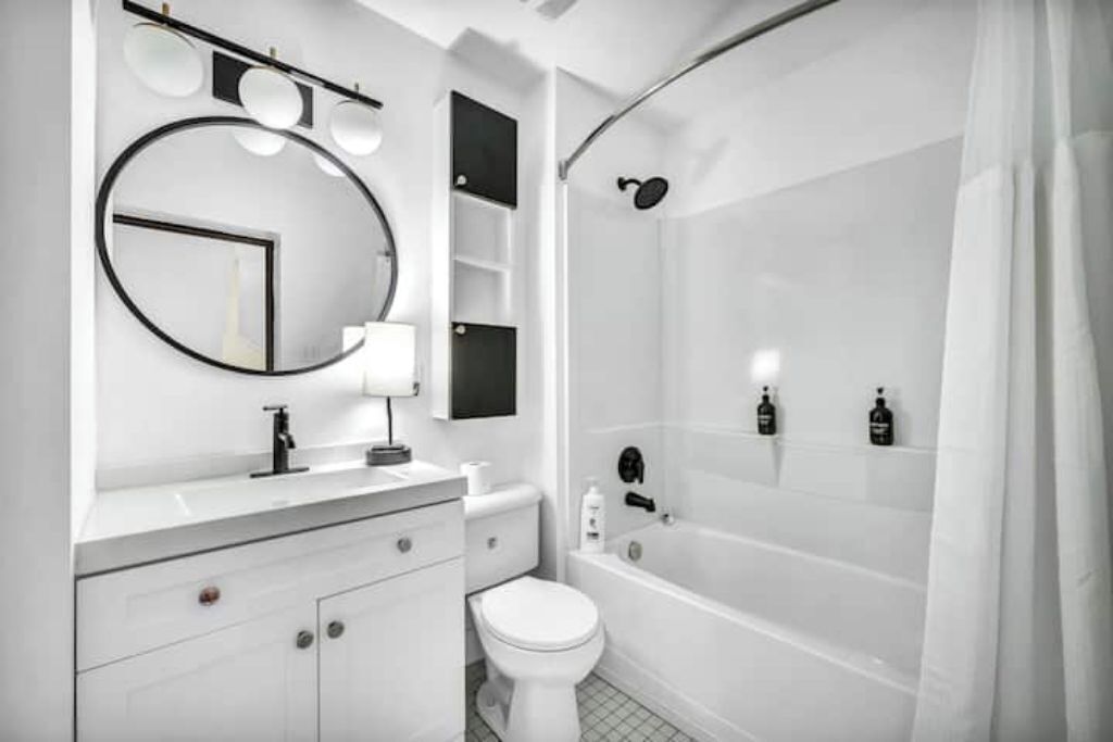 A modern bathroom with a white vanity, a toilet, a bathtub, and a shower.