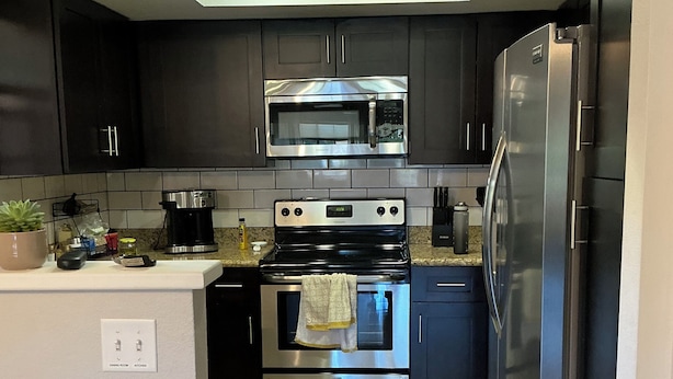 A modern kitchen with dark cabinets, a stainless steel microwave, oven, and refrigerator. - Be cool @ the pool! Quiet & private but near local attractions and conveniences! (Scottsdale)