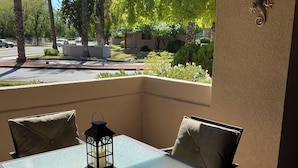 A patio with a glass table and four chairs, surrounded by a beige wall with decorative wall art. - Be cool @ the pool! Quiet & private but near local attractions and conveniences! (Scottsdale)