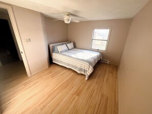 A bedroom with a bed, a ceiling fan, a window, and hardwood flooring. - Hammondsport 100ft lakefront 4 Private Docks (Hammondsport)