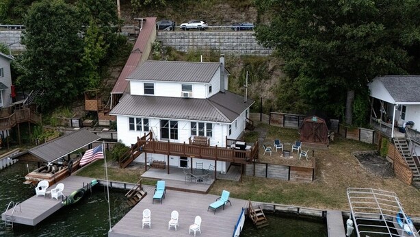 A two-story house with a dock, outdoor seating, and a barn.
