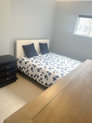 A bedroom with a bed, a dresser, a window, and a wooden table. - Hammondsport 100ft lakefront 4 Private Docks (Hammondsport)