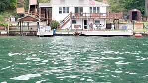 A waterfront cabin with a dock, a small deck, and a flag.