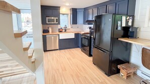 A compact kitchen with dark blue cabinets, a stainless steel refrigerator, a microwave, and a dishwasher.