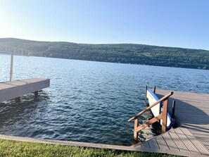 A wooden dock extending into a calm lake with a clear view of a forested hillside in the background. - Hammondsport 100ft lakefront 4 Private Docks (Hammondsport)