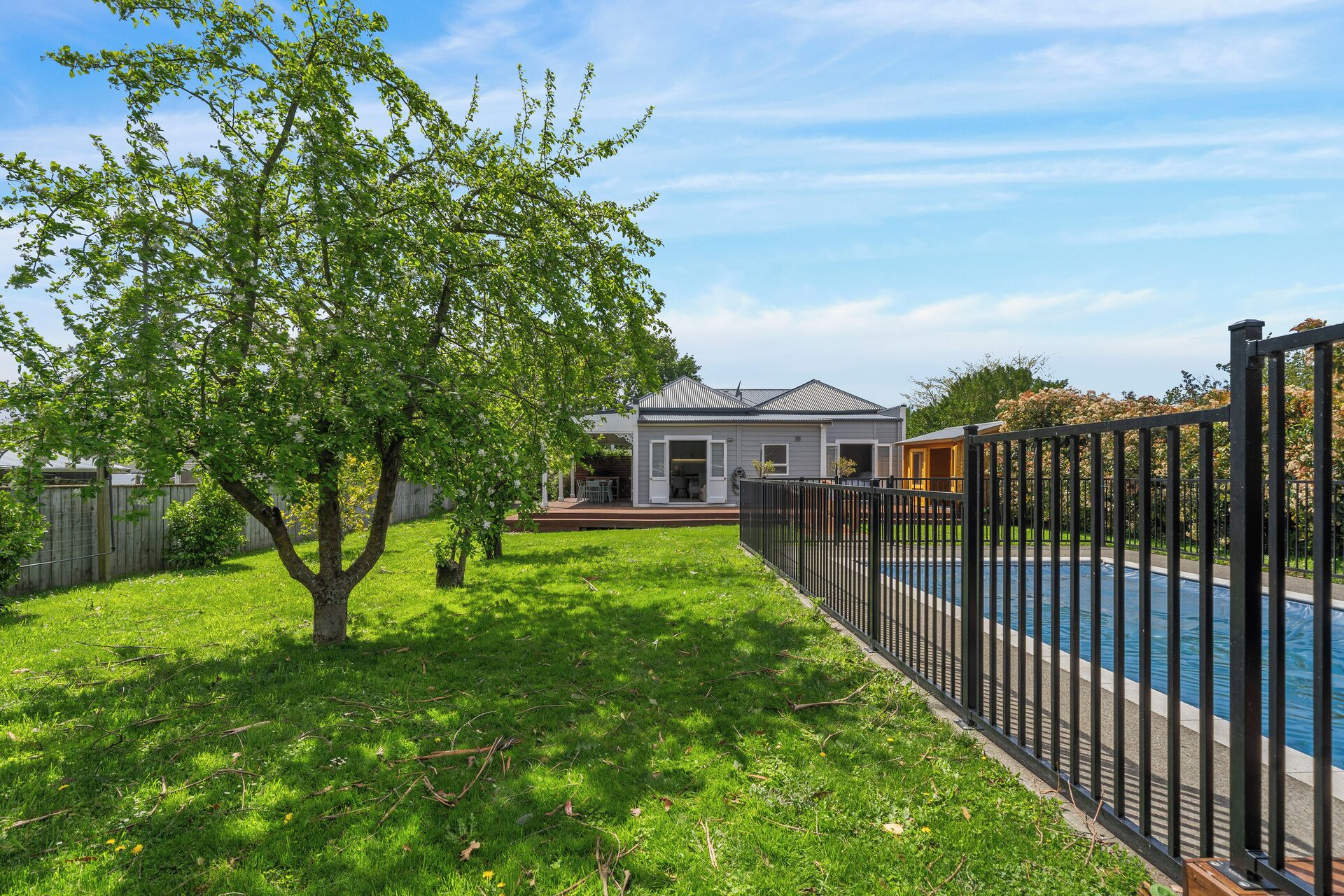 Ein Wohnhaus mit Swimmingpool, umzäunter Garten und Dach aus Metall.