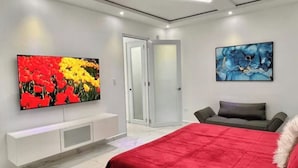 Une chambre moderne avec un grand lit, un téléviseur fixé au mur et une porte donnant sur une salle de bain.