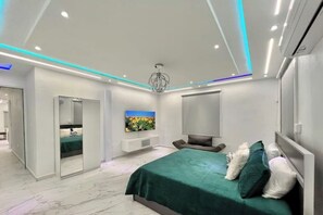 A modern bedroom with a large bed, a TV, and a walk-in closet.
