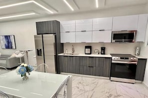 A modern kitchen with white cabinets, a built-in microwave, and a stainless steel oven.