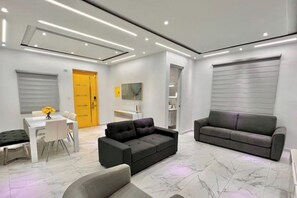 A modern living room with a sofa, a dining table with chairs, and a yellow door.
