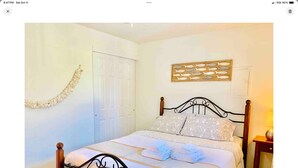 A neatly made bed with a headboard, a bedside table with a lamp, and a door in the background. - Cozy Charming and Central 1-bedroom apartment in Kent (Kent)
