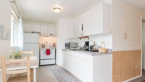 A compact kitchen with white cabinets, a stove, microwave, and a coffee maker. - Cozy Charming and Central 1-bedroom apartment in Kent (Kent)