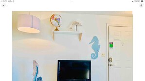 A living room with a TV on a stand, a globe, a seahorse decoration, and a lamp. - Cozy Charming and Central 1-bedroom apartment in Kent (Kent)
