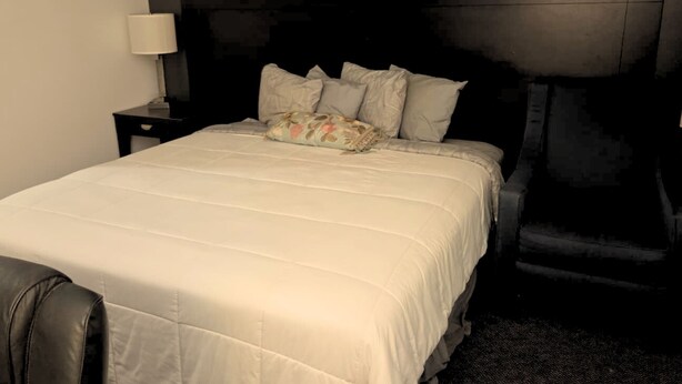 A neatly made bed with a floral pillow and a matching headboard. - Blue Way Inn By Jasper Hutchinson - Standard 1 King Bed Non Smoking (Hutchinson)