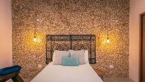 A bedroom with a stone wall, a metal headboard, and two bedside lamps. - Casa Kiiwik - Luxury Property with a Private Outdoor Pool and Parking in Central Merida (Mérida)