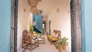 A cozy living area with wicker furniture, a staircase, and a potted plant. - Casa Kiiwik - Luxury Property with a Private Outdoor Pool and Parking in Central Merida (Mérida)