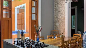 A kitchen with a central island, wooden dining table, and chairs. - Casa Axuul - Colonial Property in Central Merida (Merida)