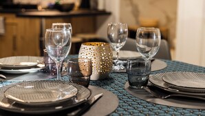 A dining table set with clear glassware, a patterned tablecloth, and a decorative candle holder. - Chez Corinne et Gilles SPA apartment on the Alsace wine route (Marlenheim)