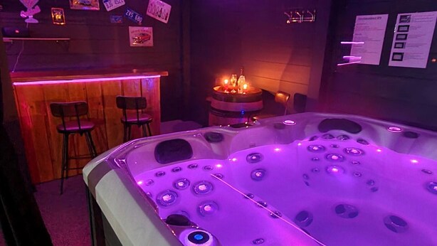 A room with a large, illuminated hot tub, wooden bar area, and a seating arrangement with chairs. - Chez Corinne et Gilles SPA apartment on the Alsace wine route (Marlenheim)