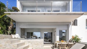 Ein modernes Haus mit Natursteinfassade, einem Pool und einer Terrasse mit Lounge-Möbeln und Essbereich.