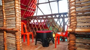 A room with a wooden floor, a black stool, and two red chairs. - Serenity Bay Home Stay Pondicherry (Pondicherry)