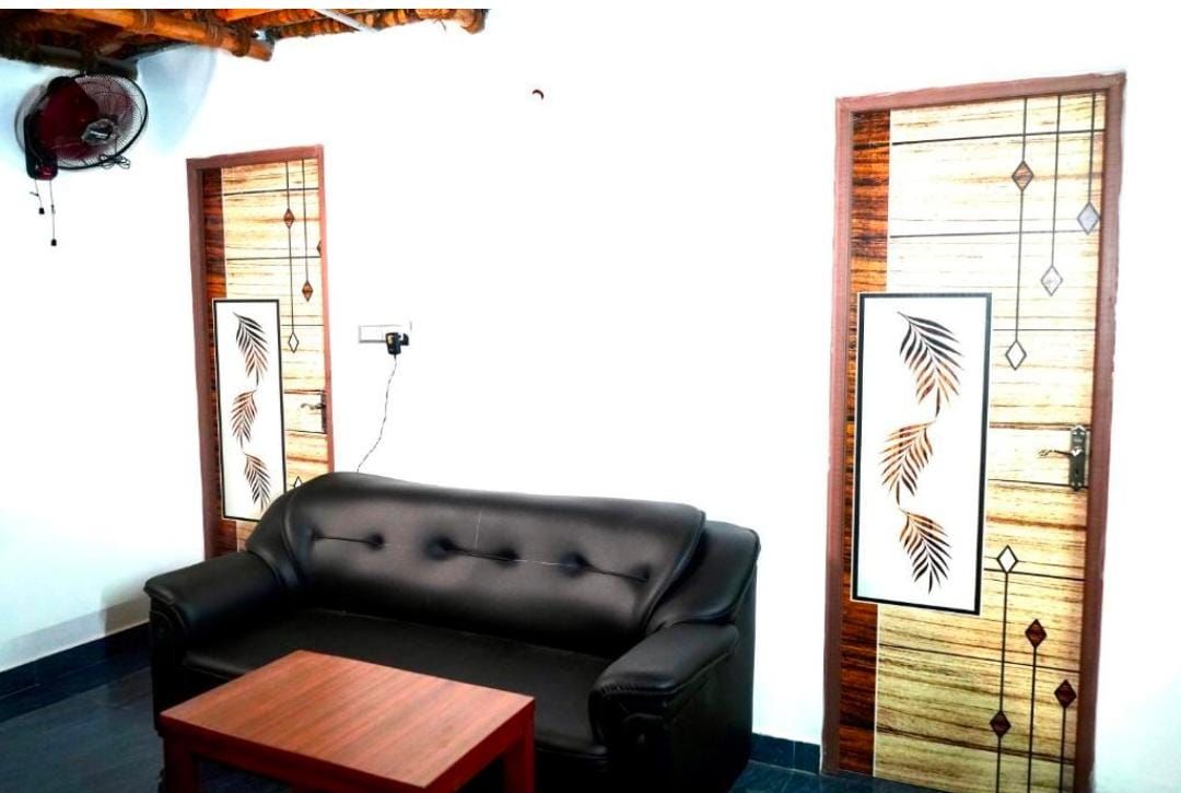 A room with a black leather sofa, a wooden coffee table, and two doors with decorative panels.