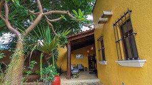 Un bâtiment jaune doté d’un patio couvert, d’une grande plante en pot et d’une statue d’éléphant.