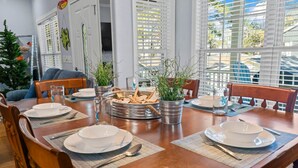 Een eettafel gedekt met borden, bestek en een serveerplank in het midden met eten en drinken.