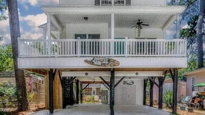 Een tweelaags huis met een balkon, een garage en een bord waarop 'The Lodge' staat.