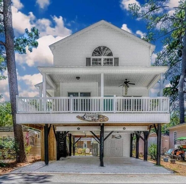 A two-story house with a balcony, a garage, and a sign that reads "The Lodge."