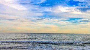 Een strand met uitzicht op de oceaan en een heldere lucht.