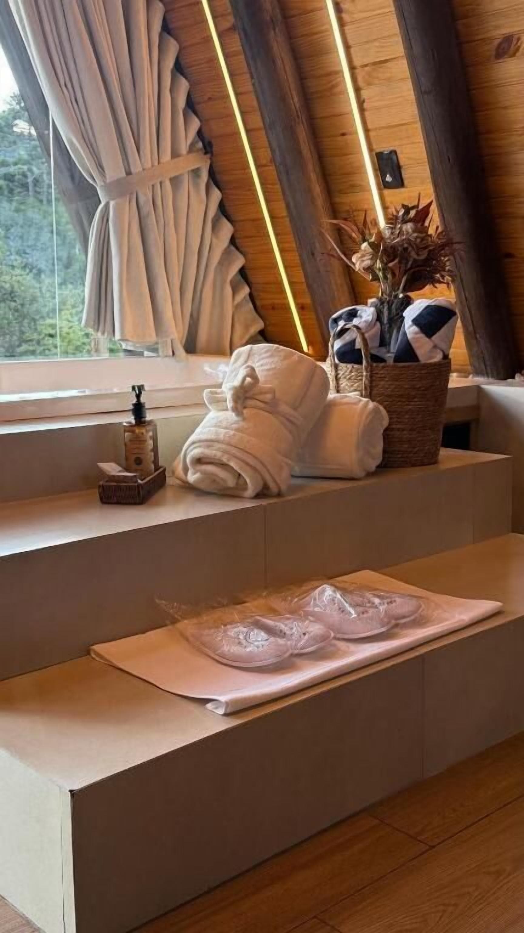 Un intérieur en bois avec une fenêtre, une serviette, un panier et une bouteille.