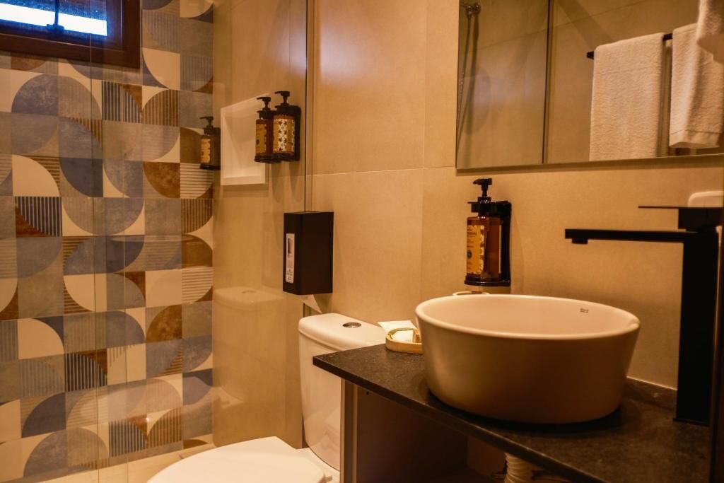 Ein Badezimmer mit Wand in geometrischem Muster, einem weißen Waschbecken und einem Spiegel darüber.