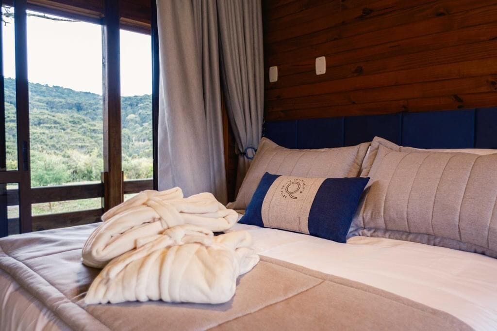 Une chambre à coucher avec un lit, une fenêtre avec des rideaux et une vue sur la verdure à l’extérieur.