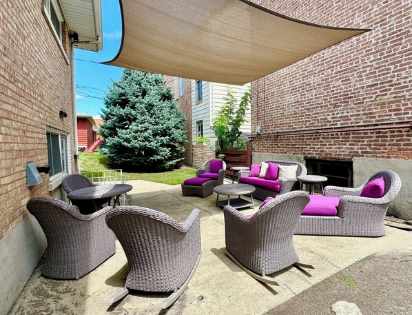 An outdoor patio with wicker furniture, a fire pit, and a brick wall.