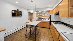 A modern kitchen with wooden cabinets, a marble countertop, and a built-in oven. - Spacious Single Family House with Parking (Chicago)